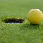 yellow golf ball near a hole