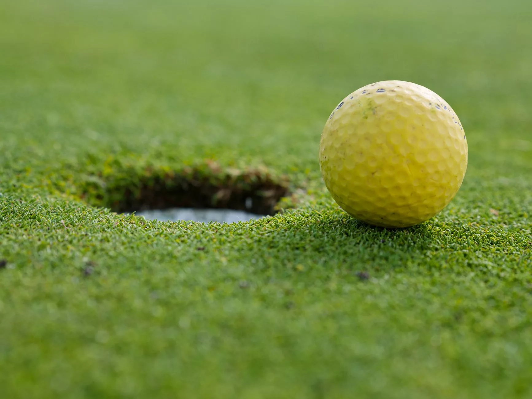 yellow golf ball near a hole